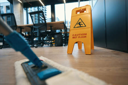 Bodenreinigung im modernen Büro mit Warnschild „Caution Wet Floor“