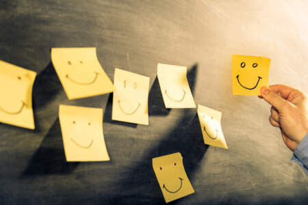 Gelbe Haftnotizen mit Smiley-Gesichtern als Symbol für Kundenzufriedenheit